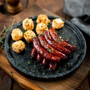 Linguiça de costela angus carapreta caramelizada na cerveja preta acompanhada de dadinhos de tapioca fritos